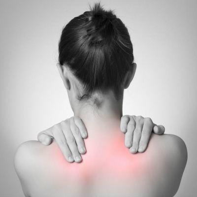 Young woman rubbing her upper back due to pain from a pinched nerve.